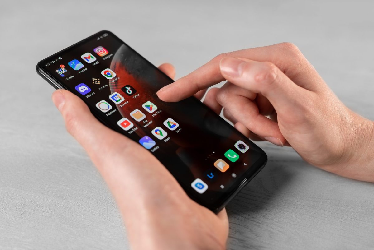 Person hält ein Android-Handy in der Hand, auf dem mehrere Apps angezeigt werden.
